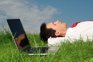 man lying on the grass with laptop
