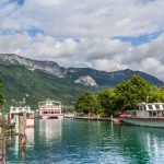 Le lac d'Annecy et ses bateaux de croisiere, avec les montagnes en arriere-plan