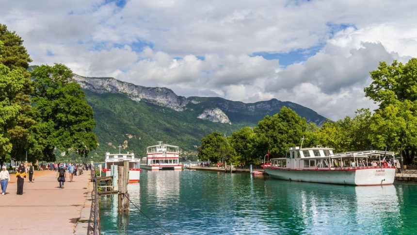Le lac d'Annecy et ses bateaux de croisiere, avec les montagnes en arriere-plan