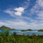Petites îles boisées entourées d'un lagon turquoise aux Seychelles, vues depuis la végétation d'un rivage