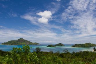 Petites îles boisées entourées d'un lagon turquoise aux Seychelles, vues depuis la végétation d'un rivage